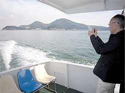船上から見える美しい島々の風景等を撮影する伊藤委員長